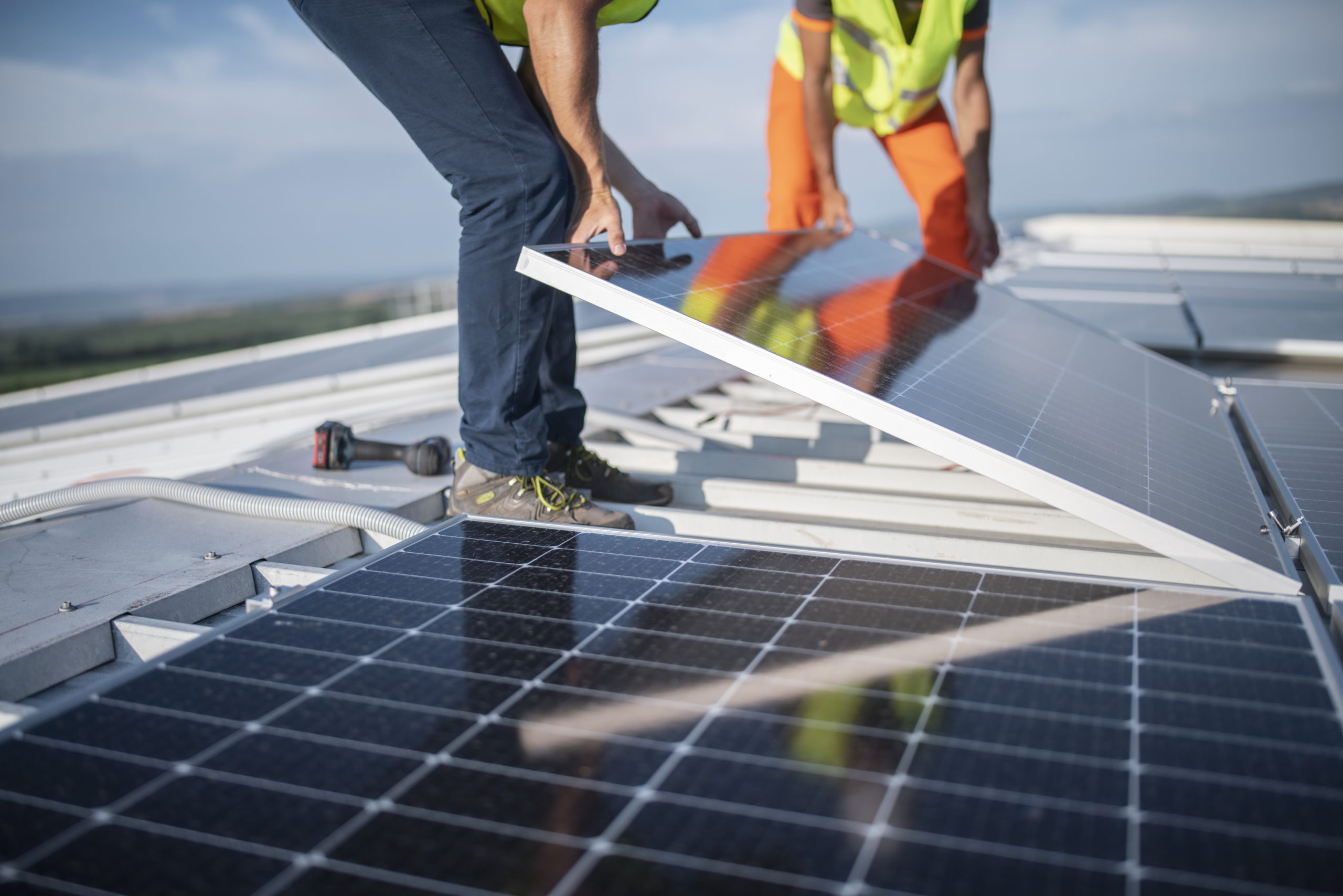 Two engineers installing solar panels on roof